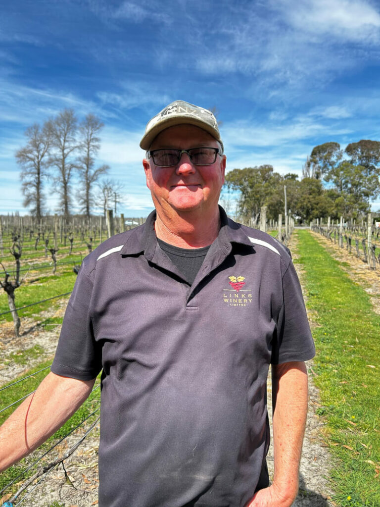 Links Winery team member standing in a Hawke’s Bay vineyard that supports wine making and contract wine making for Sauvignon Blanc, Pinot Gris and Merlot.